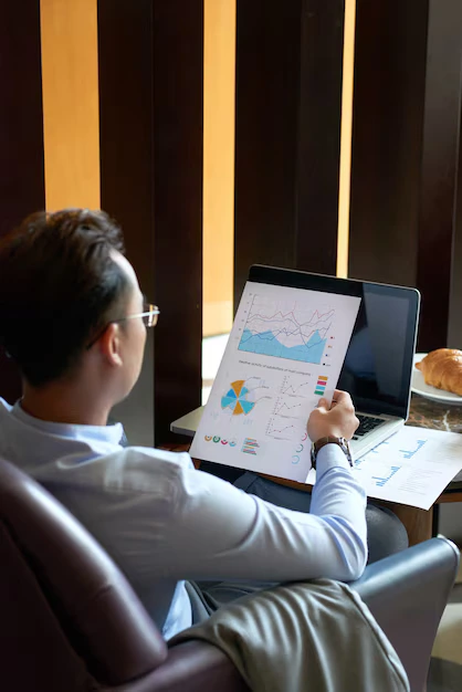 rear view man seated armchair cafe analyzing diagrams charts before presentation  